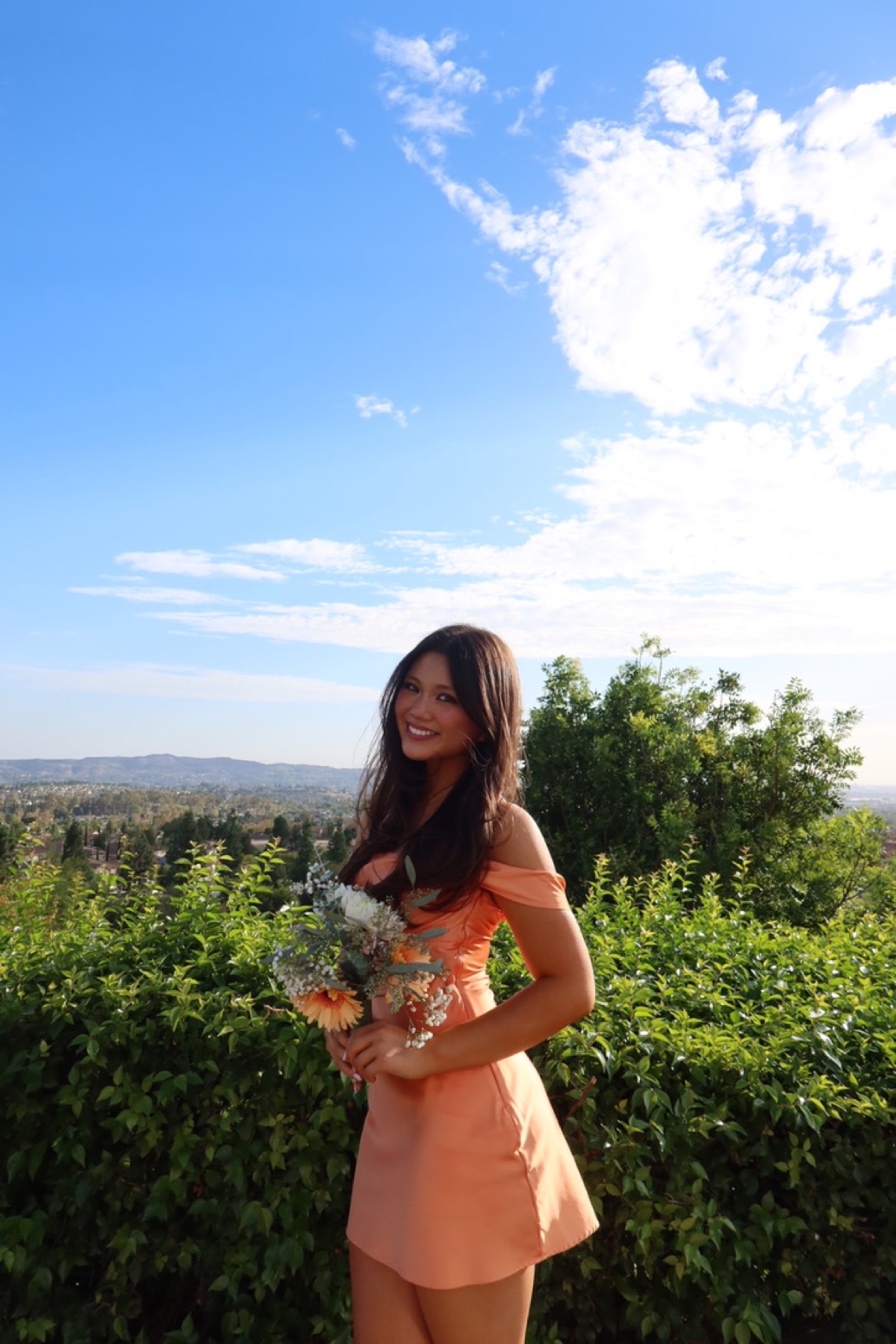 Robbie, the birthday girl, smiling outdoors in a peach dress with flowers